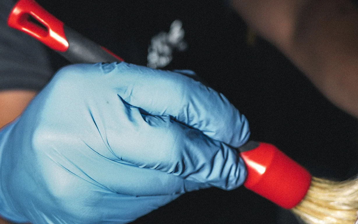 Detailpinsel in einer Hand im Nitrilhandschuh, bei der Innenreinigung